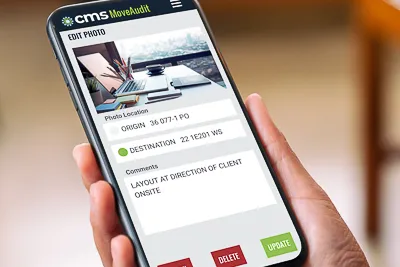 Hand holding a phone displaying CMS MoveAudit photo inventory tool